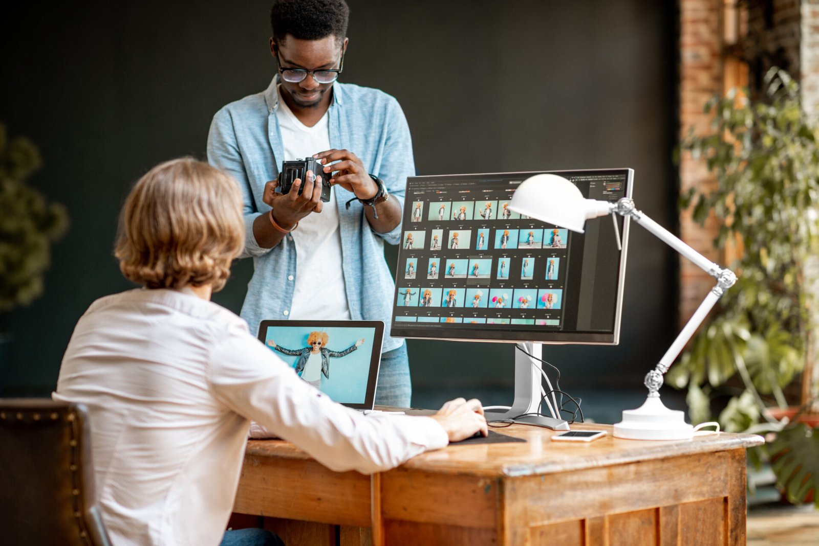 two-male-photographers-choosing-womans-portraits-at-the-working-place-with-two-computers-in-the-studio